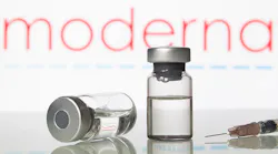 vaccine vials in front of moderna logo