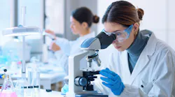 Young scientists conducting research investigations in a medical laboratory, a researcher in the foreground is using a microscope
