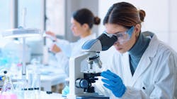 Young scientists conducting research investigations in a medical laboratory, a researcher in the foreground is using a microscope Young scientists conducting research investigations in a medical laboratory, a researcher in the foreground is using a microscope