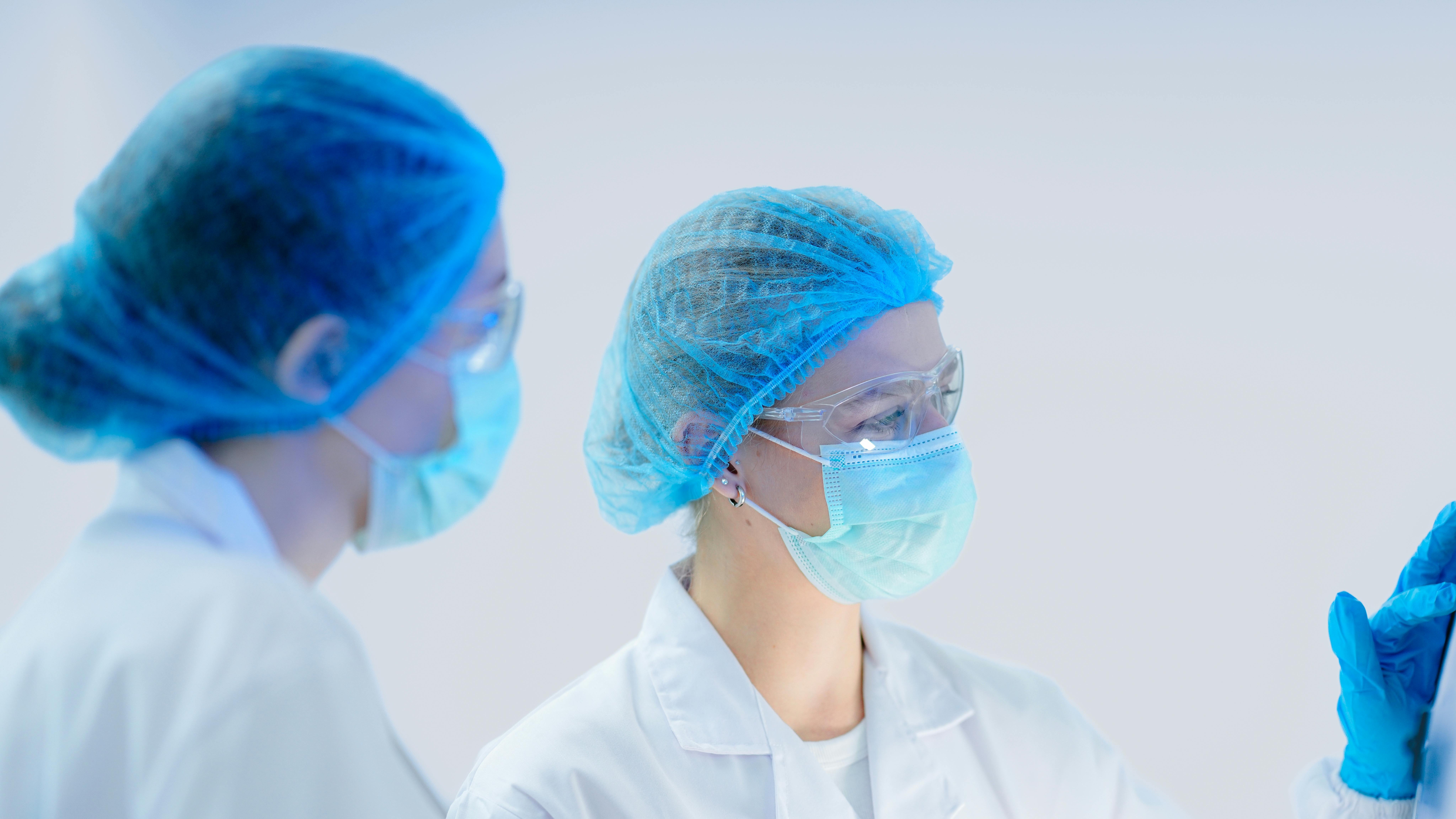 Two researchers in a GMP compliant cleanroom operate manufacturing equipment