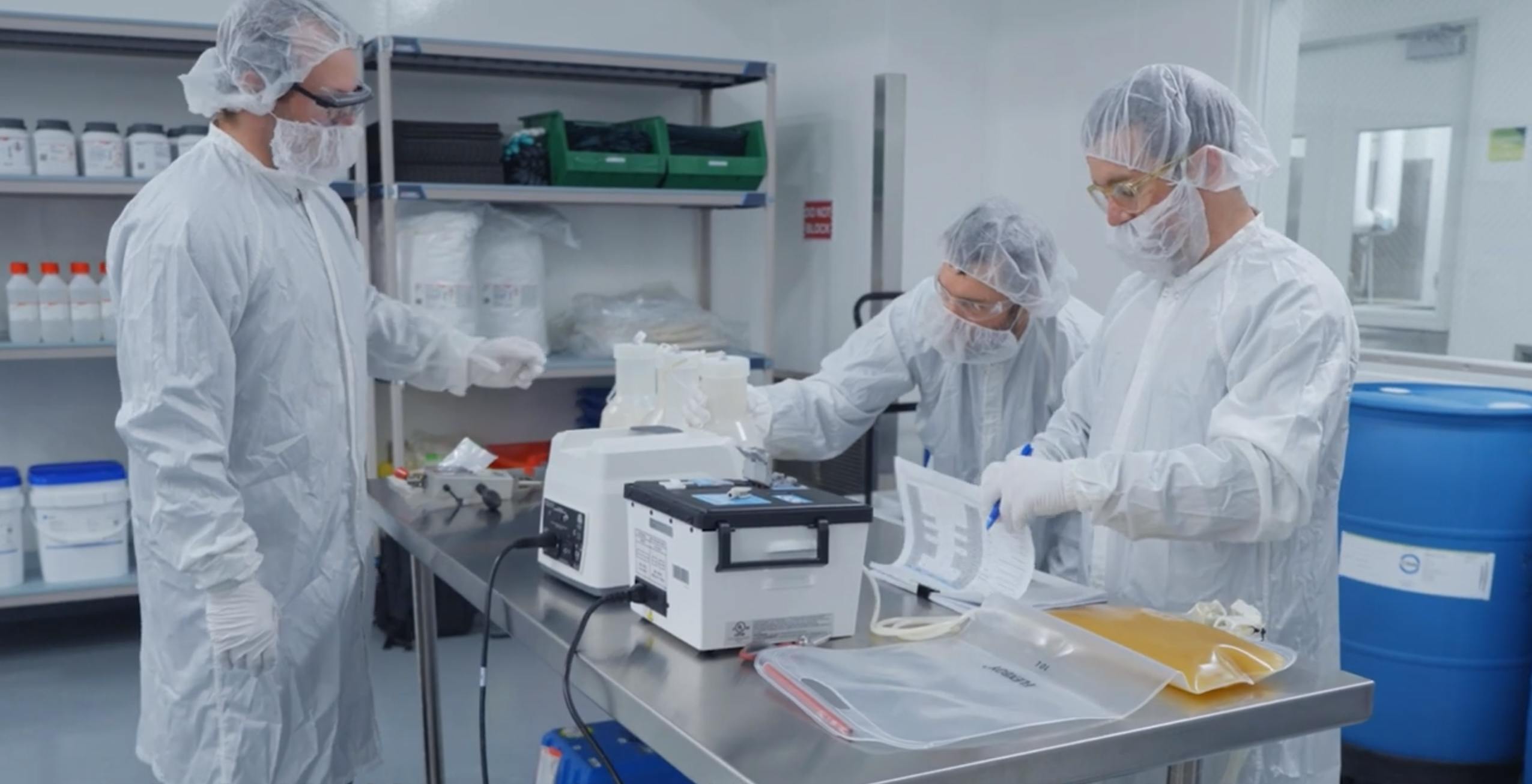 Three workers process and evaluate materials at AGC Biologics manufacturing site in Seattle