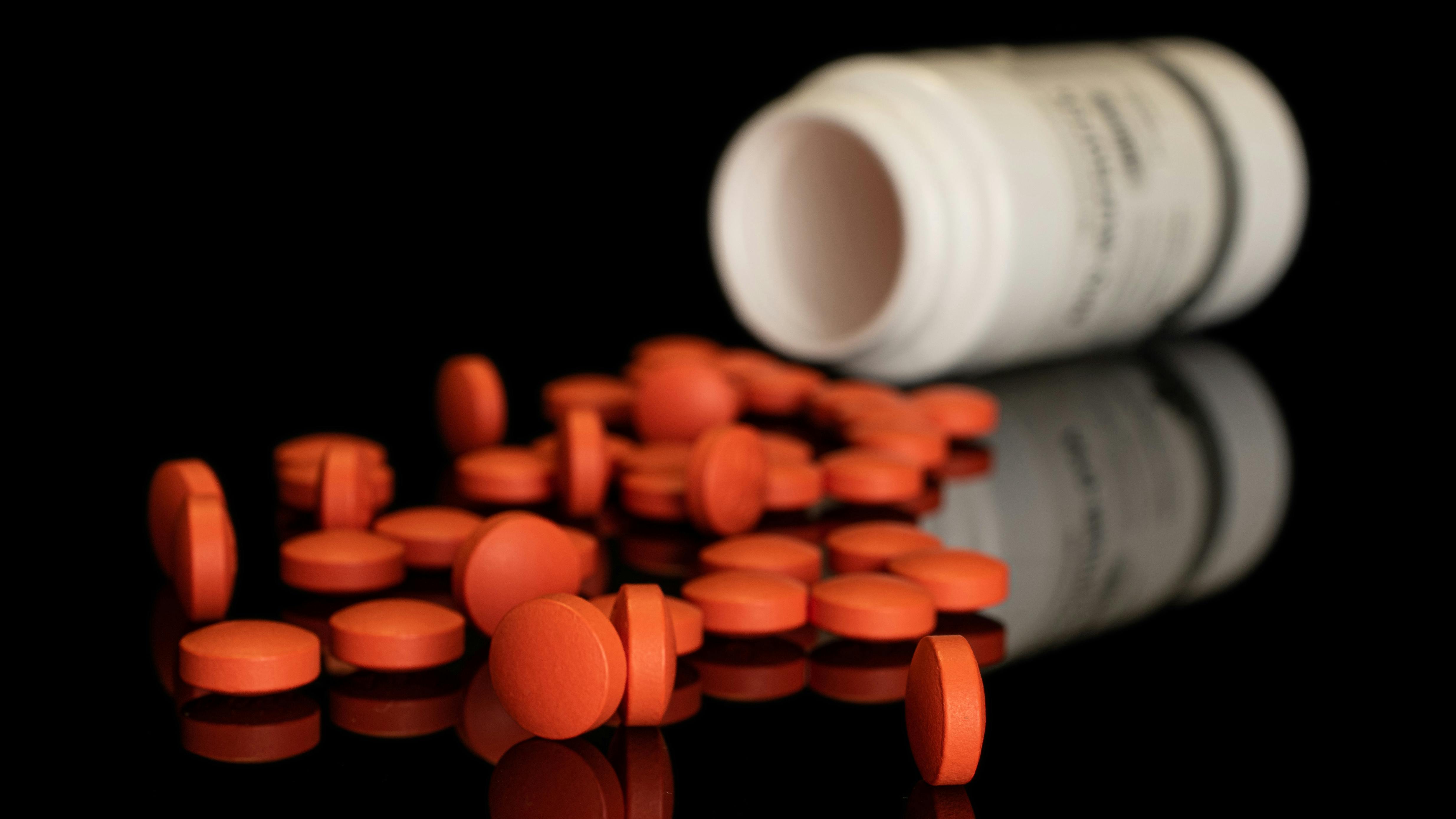 Lot of whole orange tablet pharmacy with plastic bottle isolated on black glass