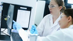 Two scientists review an electronic batch record on a tablet while a third performs a required analytical test. Two scientists review an electronic batch record on a tablet while a third performs a required analytical test.