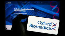 Person holding mobile phone with logo of British gene therapy company Oxford Biomedica plc in front of business web page