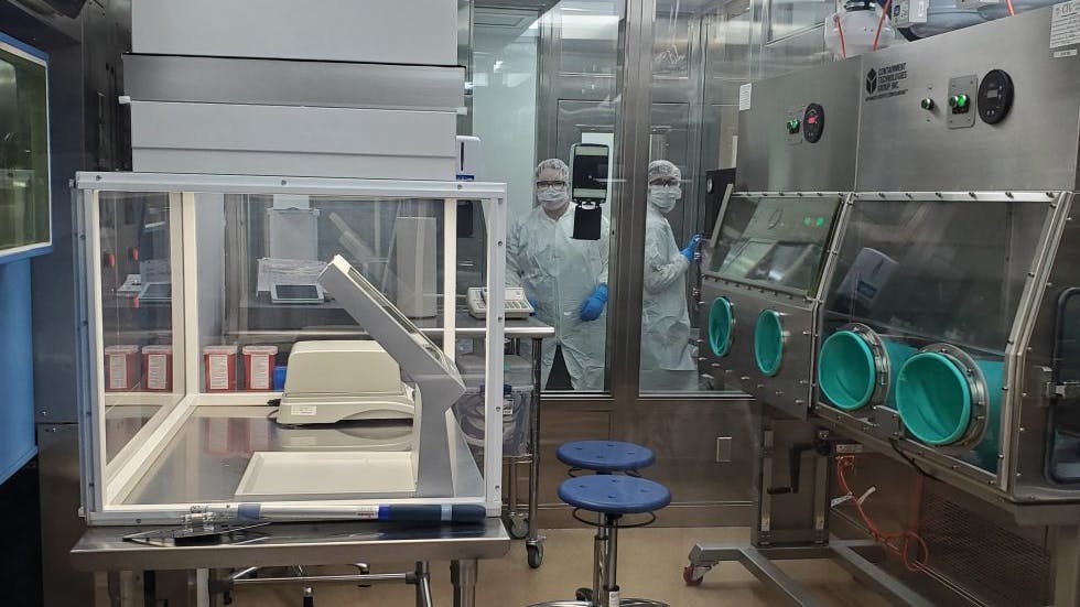 Two pharma workers in PPE at SpectronRx GMP manufacturing site