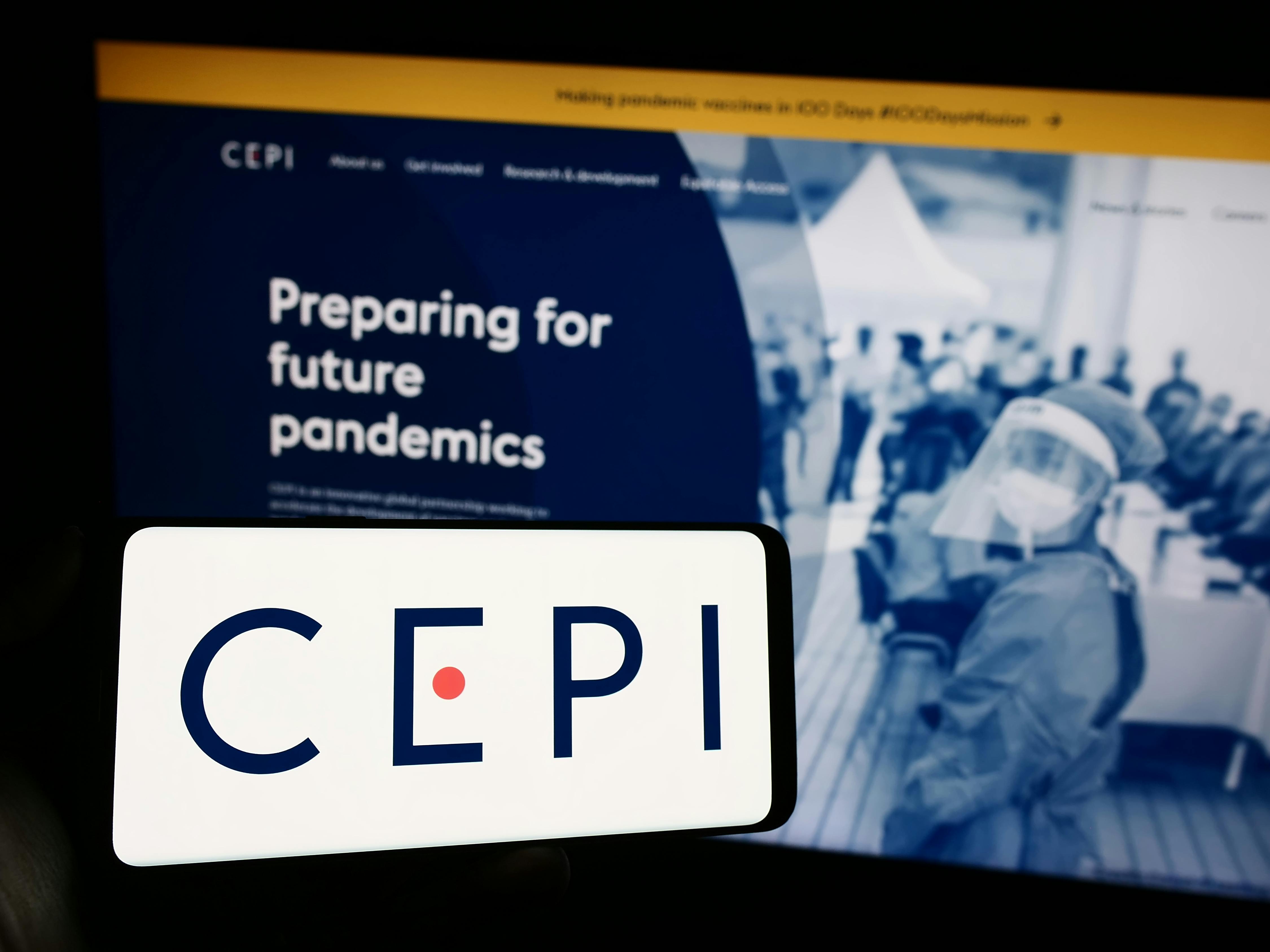 Person holding cellphone with logo of Coalition for Epidemic Preparedness Innovations (CEPI) in front of webpage.