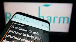 Recipharm website displayed on smartphone with logo blurred on digital screen in background