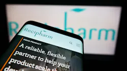 Recipharm website displayed on smartphone with logo blurred on digital screen in background Recipharm website displayed on smartphone with logo blurred on digital screen in background