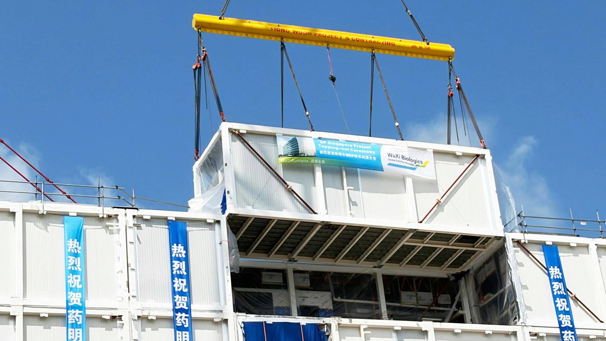 a crane lowers final section to complete the topping out of the Drug Product (DP) facility at its Singapore CRDMO Hub at WuXi Biologics
