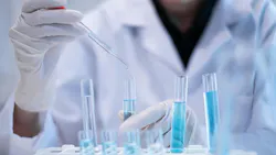 gloved hands hold test tubes filled with blue liquid and dropper gloved hands hold test tubes filled with blue liquid and dropper