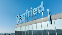 Siegfried sign on top of headquarters building against a blue sky. Landscape reflects in the building windows. Siegfried sign on top of headquarters building against a blue sky. Landscape reflects in the building windows.