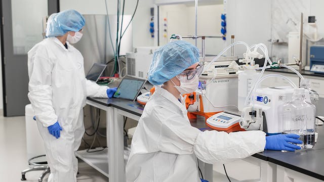 Pharmaceutical workers in PPE in lab at new TriLink facility