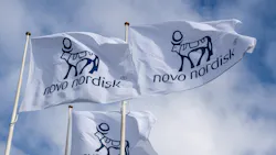 Flags with Novo Nordisk logo wave in wind against clouds and blue sky Flags with Novo Nordisk logo wave in wind against clouds and blue sky