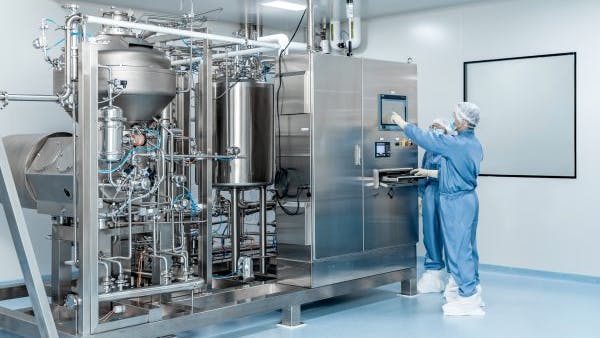 Two workers at control panel of pharma manufacturing equipment at WuXi Biologics facility