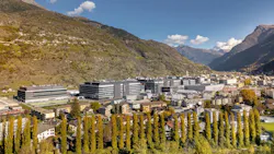 Aerial view overlooking several buildings that make up the Lonza site in Visp, Switzerland. Mountains in the background