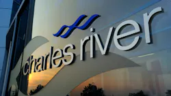 Close up view of Charles River logo on glass building that reflects sky at dusk