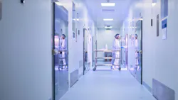 Image of hallway where worker in PPE pushes cart into lab at Touchlight