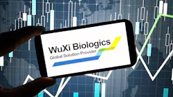 hand holds cell phone with WuXi Biologics logo on screen with digital graphics in background