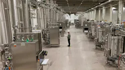 Worker stands inside large ABEC manufacturing facility