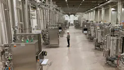 Worker stands inside large ABEC manufacturing facility