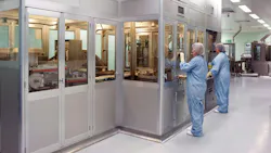 Two workers in PPE stand in front of pharma operations enclosure at Bespak facility in Holmes Chapel, UK