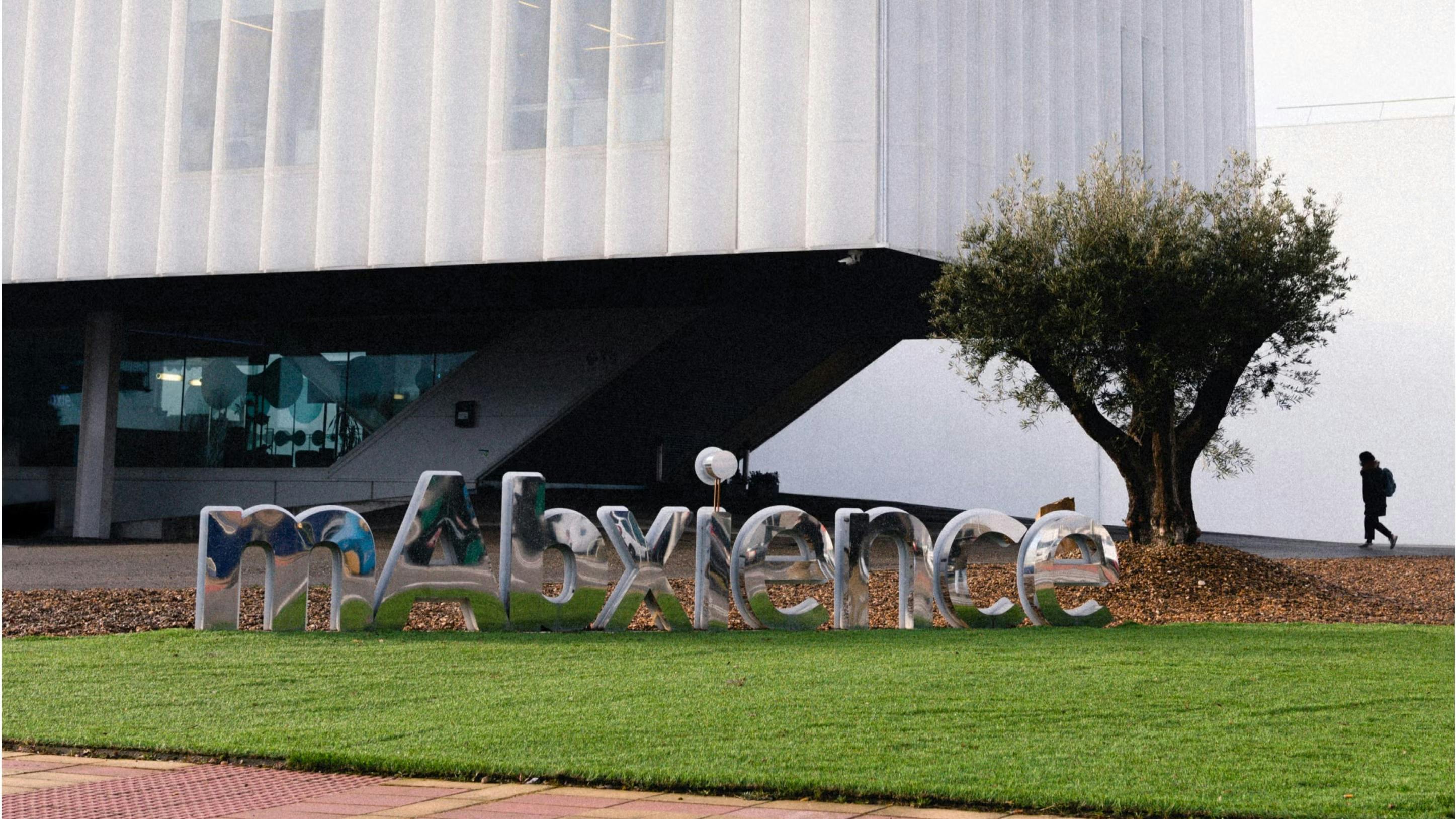 MAbxience campus with sign in foreground and building with person walking in the background
