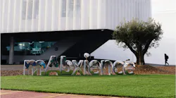 MAbxience campus with sign in foreground and building with person walking in the background